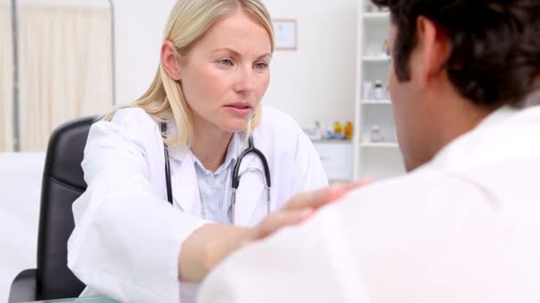 Серьёзный врач трогает плечо пациентки — стоковое видео