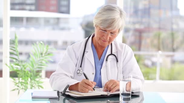 Médico maduro serio escribiendo en su calendario — Vídeos de Stock