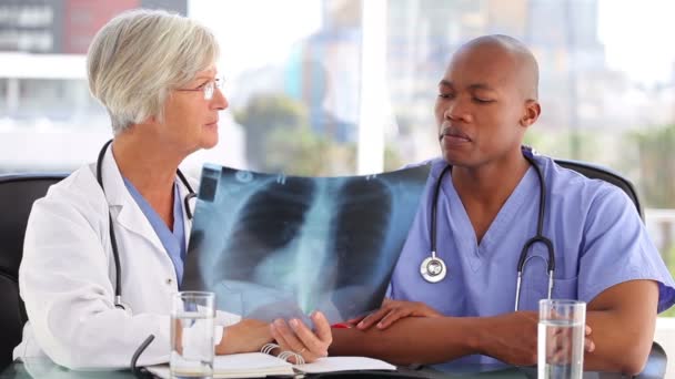 Equipa médica séria a olhar para uma radiografia de tórax — Vídeo de Stock
