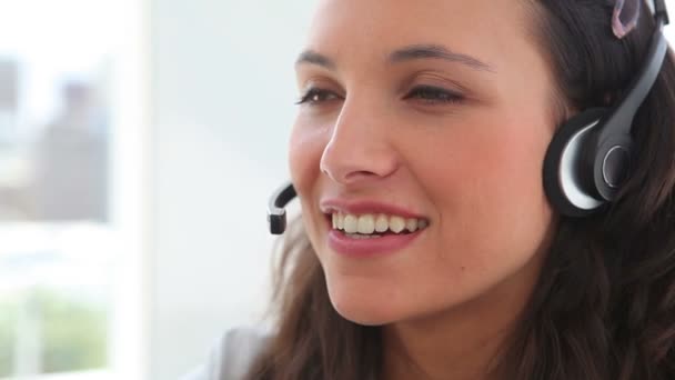 Mujer de negocios sonriendo mientras habla con un auricular — Vídeos de Stock