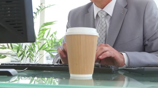 Businessman drinking a cup of coffee while typing — Stock Video