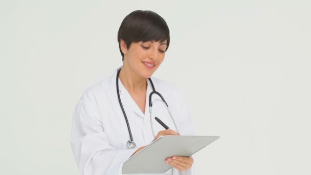 Feliz doctor escribiendo en un portapapeles — Vídeos de Stock