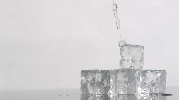 Trickle of water in a super slow motion flowing on ice cubes and falling it — Stock Video