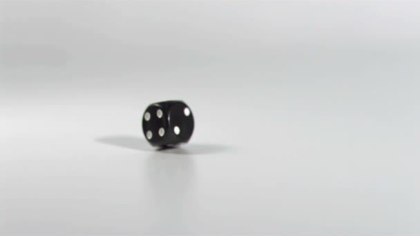 Ein schwarzer Würfel in Superzeitlupe, der sich auf dem Boden dreht — Stockvideo