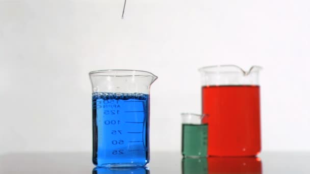 Syringe in a super slow motion falling on a blue beaker — Stock Video