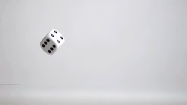 One white dice in super slow motion rebounding and turning on the grey floor — Stock Video