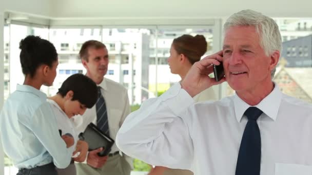 Glücklicher Direktor am Telefon mit Mitarbeiter im Hintergrund — Stockvideo
