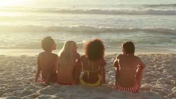 Quatro garotas se sentam na praia juntas — Vídeo de Stock