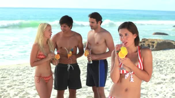 Two girls and guys standing together on the beach — Stockvideo