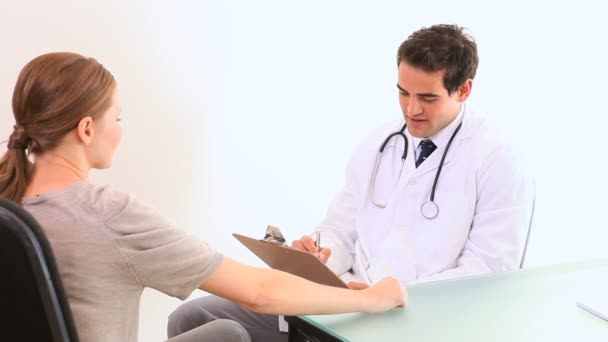 Arzt spricht mit einem Patienten, während er Informationen schreibt — Stockvideo
