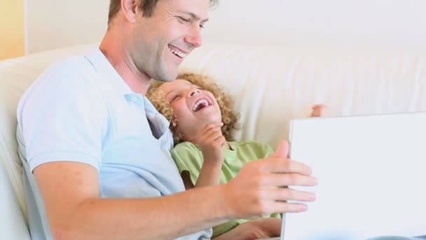 Jongen lachen tijdens het kijken naar video met zijn vader — Stockvideo