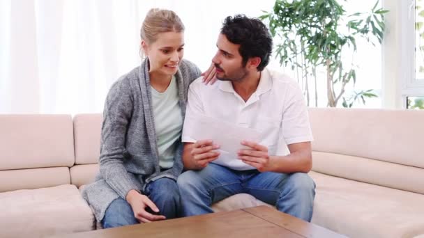 Hombre abriendo un sobre mientras está sentado junto a su novia — Vídeos de Stock