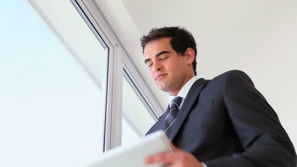 Empresario usando una tableta al lado de una ventana — Vídeos de Stock