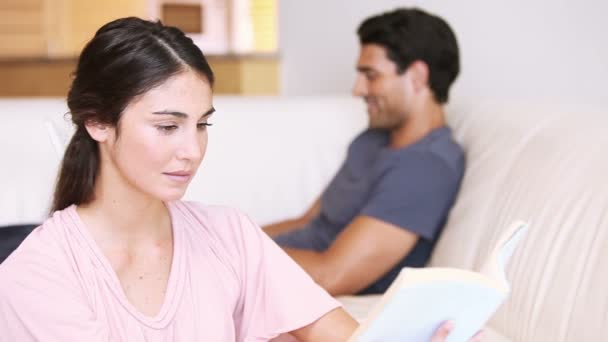 Giovane donna che legge un libro di fronte al suo fidanzato — Video Stock