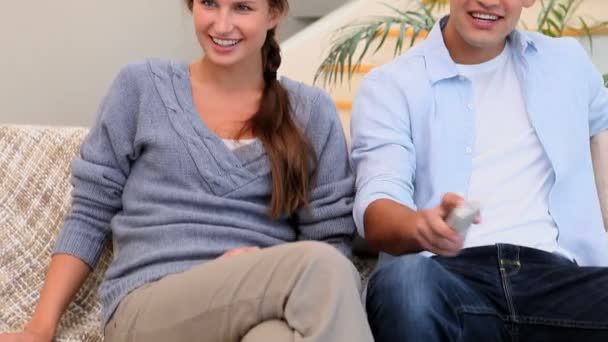 Man and woman sitting on the couch watching TV — Stock Video