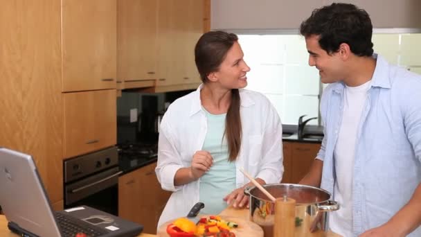 Laughing couple looking a recipe on a laptop — Stock Video