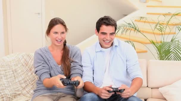 Mann und Frau sitzen auf der Couch und spielen Konsolenspiele — Stockvideo