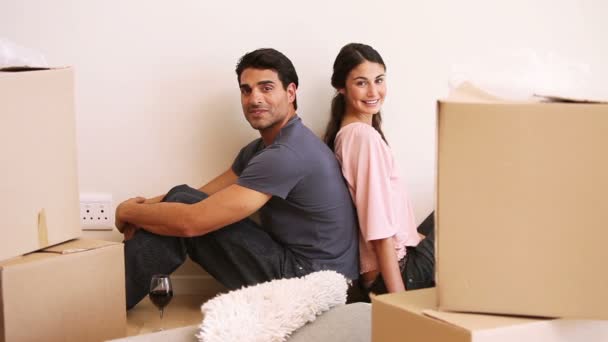 Couple sitting back to back in a room with boxes — Stock Video