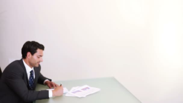 Un hombre de negocios sentado en un escritorio mientras una mujer de negocios entra — Vídeos de Stock