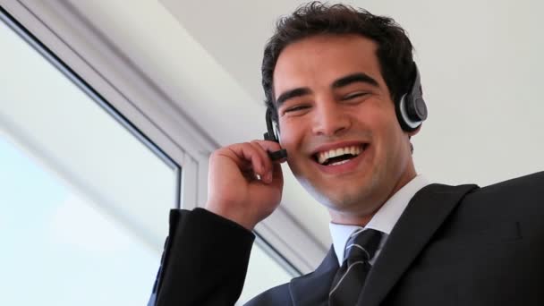 Homem de negócios usando fone de ouvido enquanto ri — Vídeo de Stock