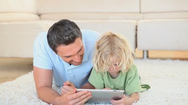 Menino loiro usando um computador tablet com seu pai — Vídeo de Stock