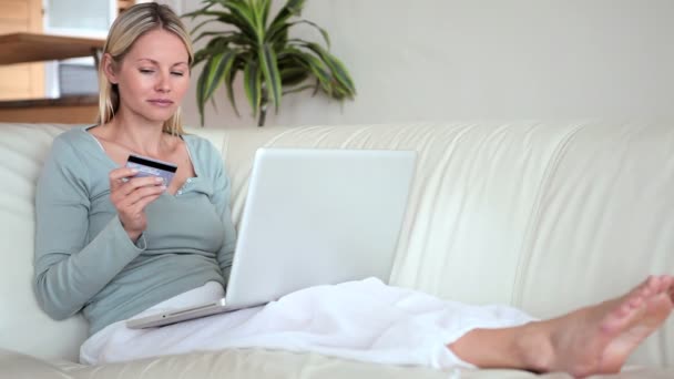 Mulher com um laptop está segurando um cartão bancário — Vídeo de Stock