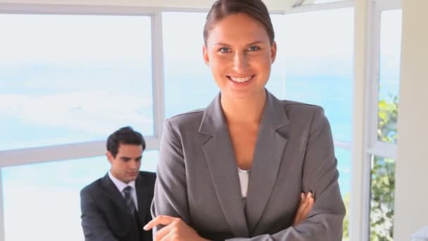 Mujer de negocios posando mientras su colega está en su escritorio — Vídeos de Stock