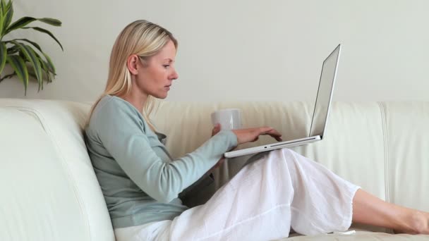 Donna che beve caffè con un computer portatile in ginocchio — Video Stock