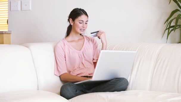Senhora sentada no sofá enquanto usa seu cartão de crédito — Vídeo de Stock