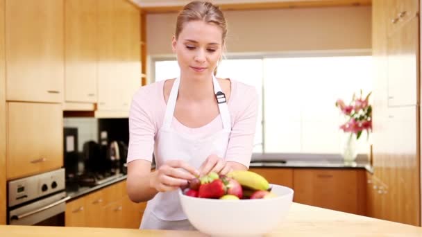 Junge Frau stellt eine Schale mit Obst auf die Arbeitsplatte — Stockvideo