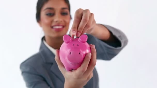 Lächelnde Brünette legt Geldscheine in ein Sparschwein — Stockvideo