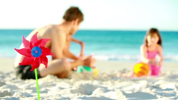 Père aidant ses enfants à faire un château de sable — Video