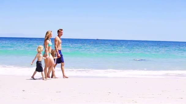 Famille souriante marchant sur le sable — Video