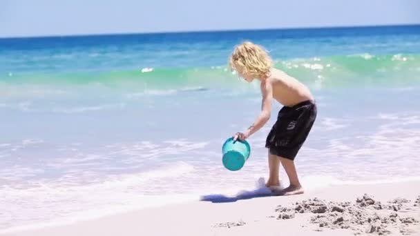 Niño rubio llenando su cubo con agua — Vídeos de Stock