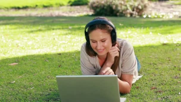 Mujer usando un ordenador portátil está escuchando música — Vídeo de stock