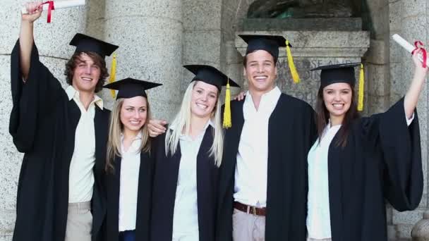 Happy estudantes abraçando enquanto segurando diplomas — Vídeo de Stock