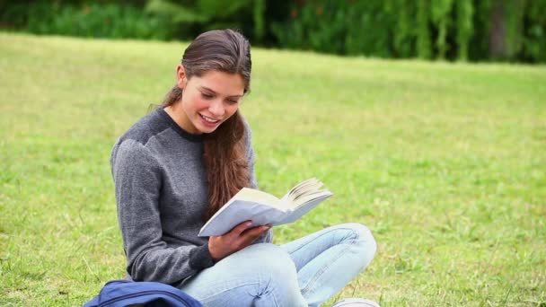 Brünette lächelt aufmerksam und liest ein Buch — Stockvideo