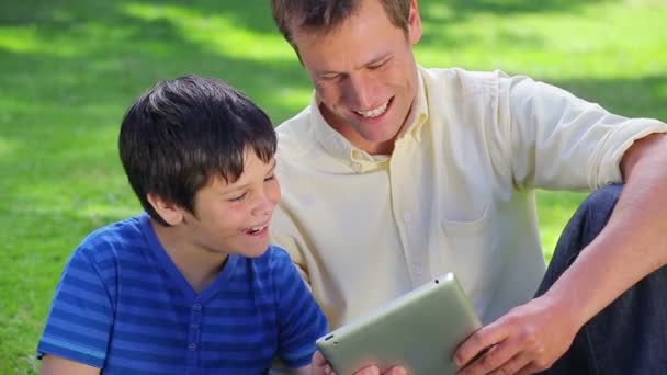 微笑着和他的儿子使用 tablet pc 的男人 — 图库视频影像