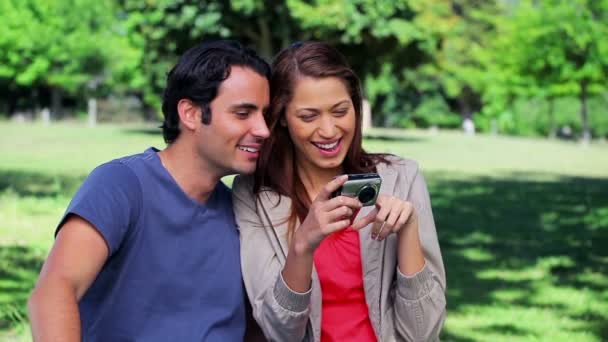 Couple souriant regardant un appareil photo numérique — Video