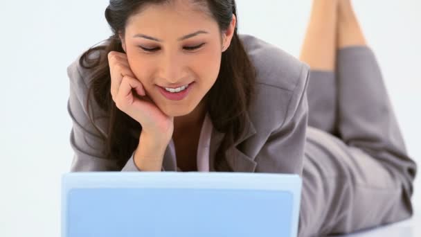 Mujer sonriente usando un portátil mientras miente — Vídeos de Stock