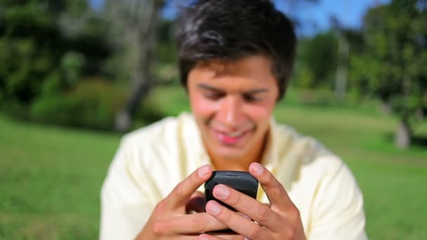 Sonriente morena hombre usando su teléfono celular — Vídeos de Stock