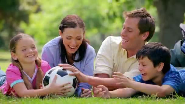 Улыбающаяся семья пытается поймать футбольный мяч — стоковое видео