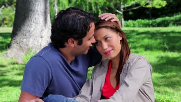 Happy couple embracing each other while sitting on the grass — Stock Video