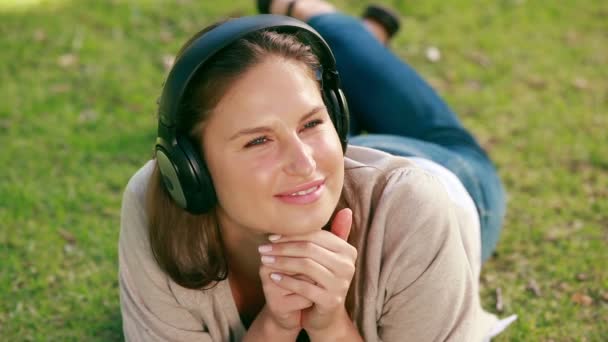 Mujer acostada en su frente escuchando música — Vídeos de Stock