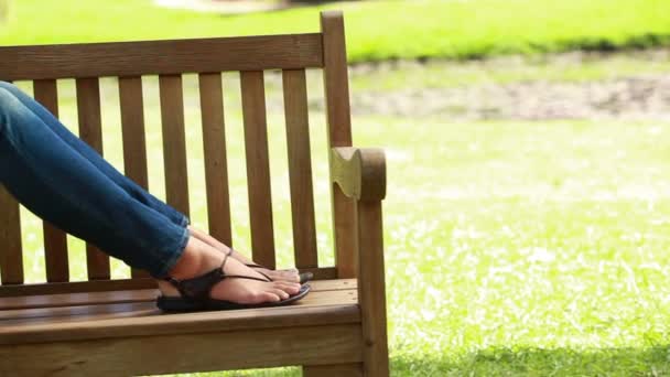 Vrouw leest een boek zittend in een park — Stockvideo