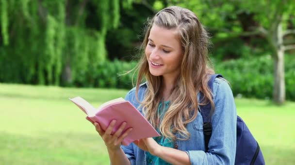 Sorrindo jovem mulher olhando para um livro — Vídeo de Stock