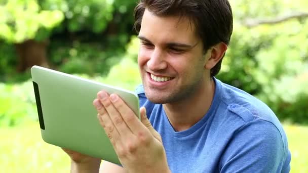 Uomo sorridente utilizzando il suo computer tablet — Video Stock