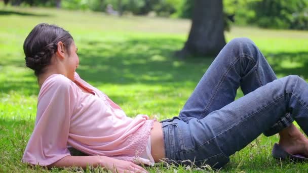 Lächelnde Frau im Gras liegend — Stockvideo