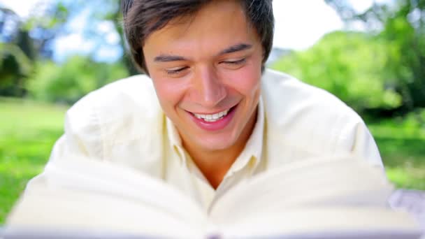 Uomo sorridente che legge un romanzo interessante — Video Stock