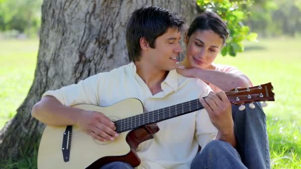 Sorrindo homem tocando guitarra para sua namorada — Vídeo de Stock